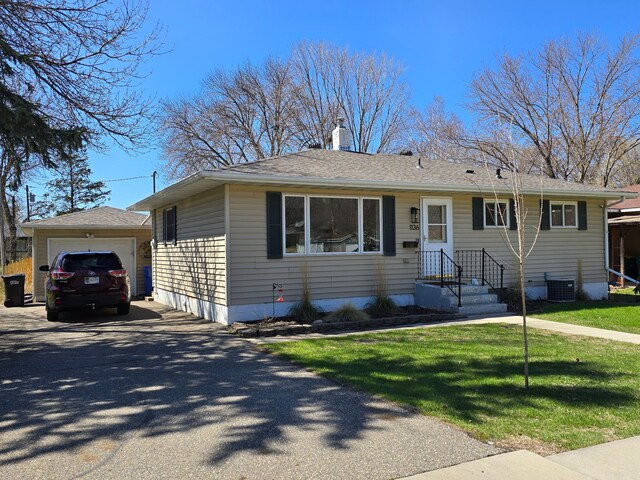 view of front of property with central AC, aphalt driveway, a garage, an outbuilding, and a chimney
