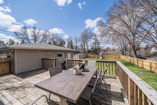 deck featuring a fenced backyard, a storage unit, outdoor dining area, and a lawn