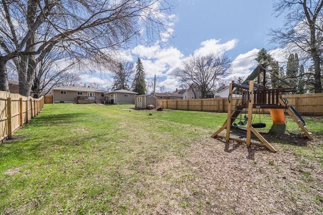 view of yard with a playground, an outbuilding, a fenced backyard, and a shed