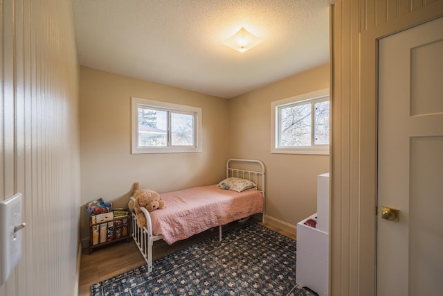 bedroom with wood finished floors and multiple windows