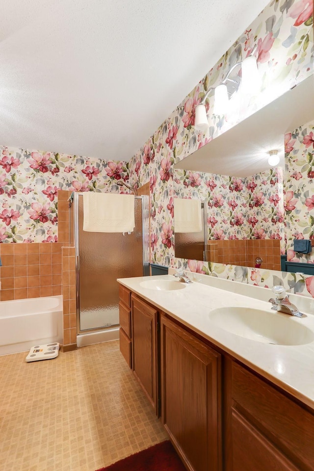 full bathroom with double vanity, a sink, a stall shower, and wallpapered walls