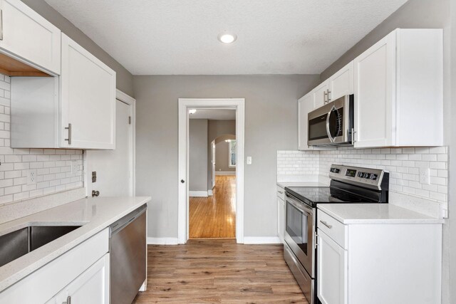 kitchen with light wood-style floors, baseboards, appliances with stainless steel finishes, and white cabinetry