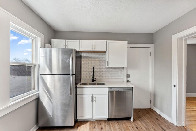 kitchen featuring backsplash, a sink, light countertops, white cabinets, and stainless steel appliances