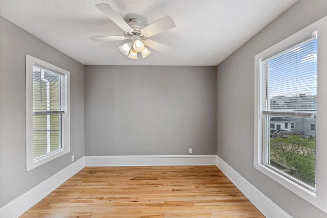 spare room with baseboards, plenty of natural light, and light wood-type flooring