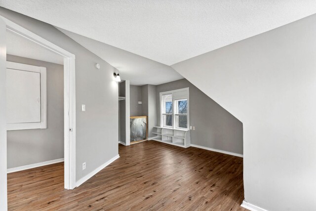 additional living space with baseboards and wood finished floors