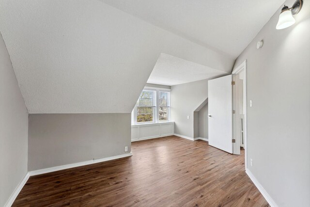 bonus room with baseboards, wood finished floors, and lofted ceiling