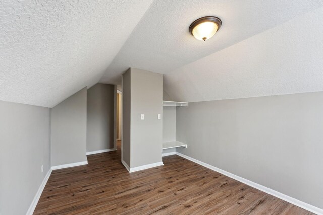 bonus room with baseboards, a textured ceiling, and wood finished floors