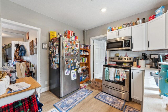kitchen featuring light wood-style floors, light countertops, white cabinets, and stainless steel appliances