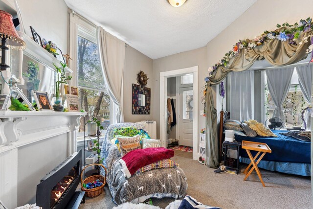 interior space featuring carpet flooring, radiator, a textured ceiling, and a fireplace