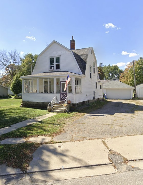 dutch colonial with a garage, a chimney, a front yard, and a gambrel roof
