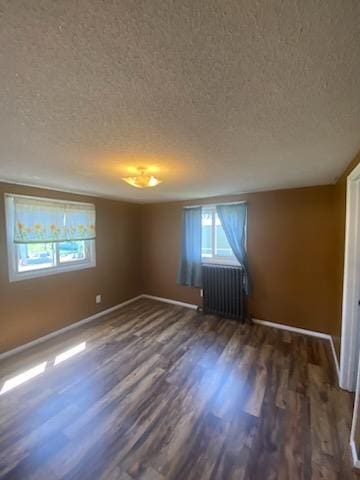 528 Broadway St, Spring Valley, MN 55975 - empty room with a textured ceiling, radiator, baseboards, and wood finished floors