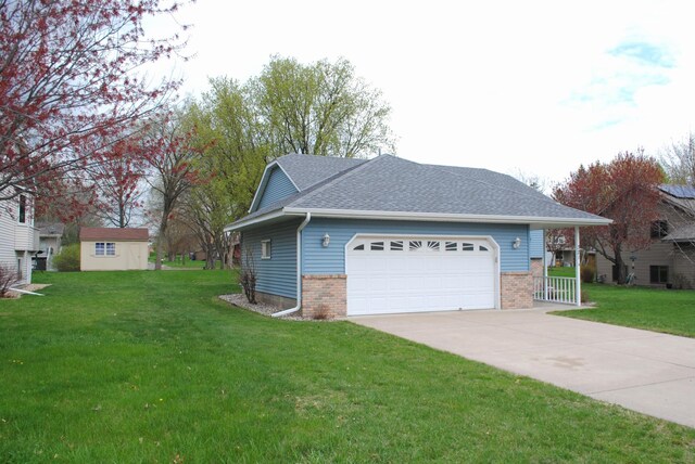 view of home's exterior featuring a garage, a yard, driveway, and brick siding