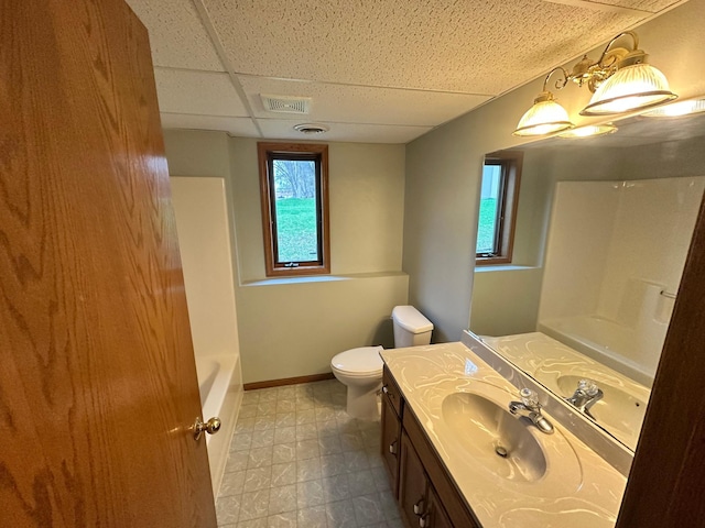 bathroom with vanity, toilet, a paneled ceiling, baseboards, and visible vents
