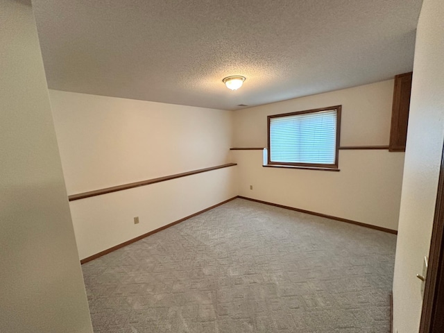 spare room with baseboards, light carpet, and a textured ceiling