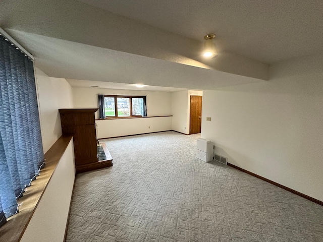 basement with baseboards, a textured ceiling, and carpet