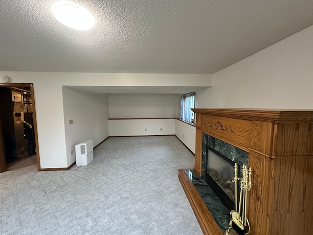 unfurnished living room featuring carpet floors, a textured ceiling, baseboards, and a high end fireplace