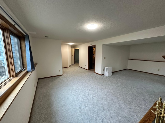 basement with baseboards, a textured ceiling, and light carpet