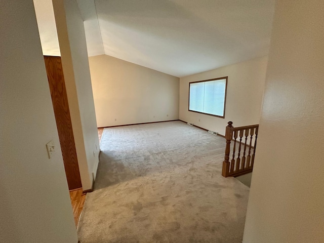carpeted spare room with baseboards and vaulted ceiling