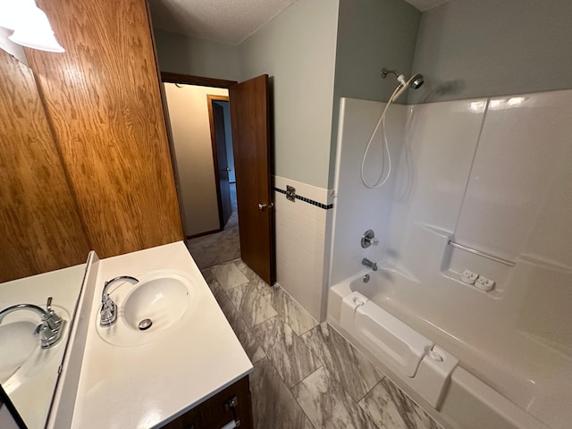 full bath with vanity, shower / bathtub combination, a textured ceiling, and marble finish floor