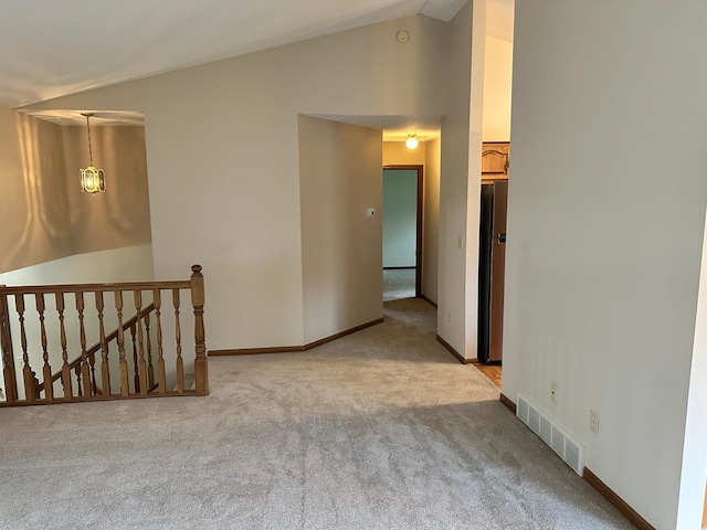 spare room with carpet floors, baseboards, visible vents, and vaulted ceiling