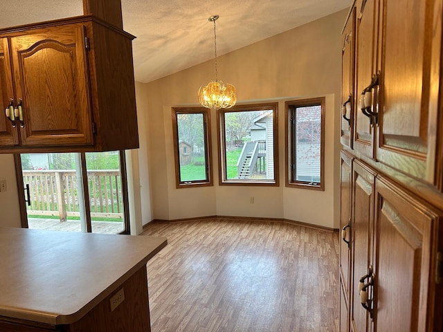 unfurnished dining area featuring light wood-style floors, baseboards, vaulted ceiling, and a notable chandelier