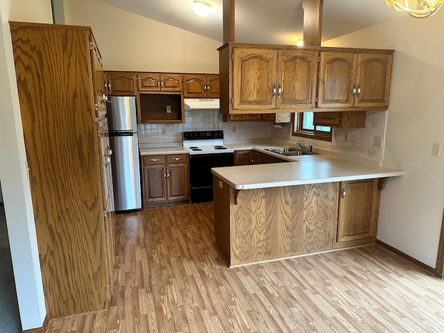 kitchen with electric range oven, freestanding refrigerator, a peninsula, light wood-style floors, and under cabinet range hood
