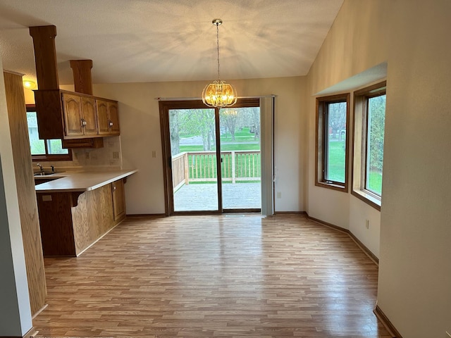 unfurnished dining area with an inviting chandelier, a healthy amount of sunlight, and light wood-style flooring