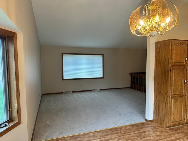 interior space with visible vents, light wood finished floors, baseboards, and a notable chandelier