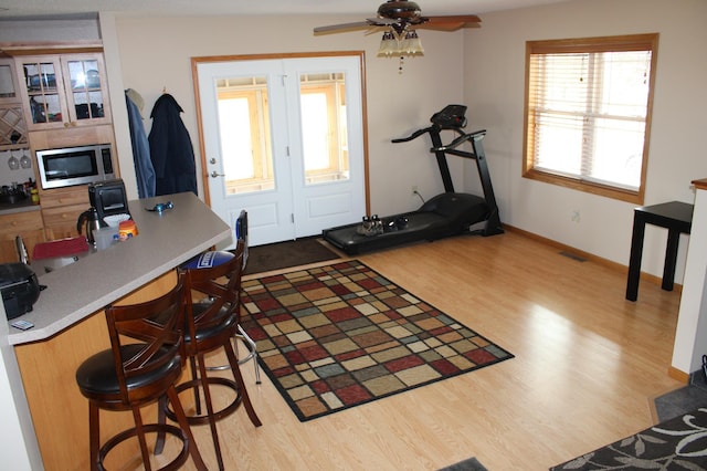 interior space featuring baseboards, a ceiling fan, wood finished floors, and visible vents