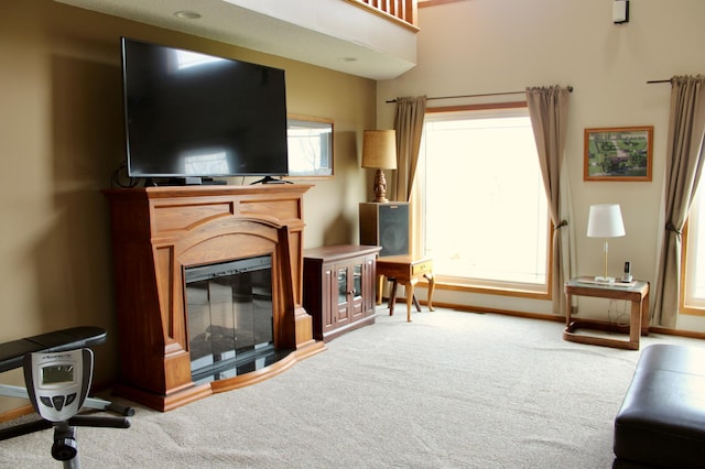 living room featuring a glass covered fireplace, baseboards, and carpet flooring