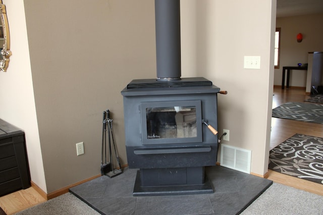 interior details featuring baseboards, a wood stove, wood finished floors, and visible vents