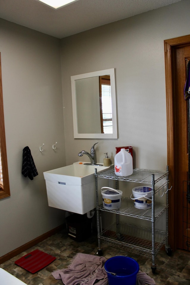 bathroom featuring baseboards and a sink