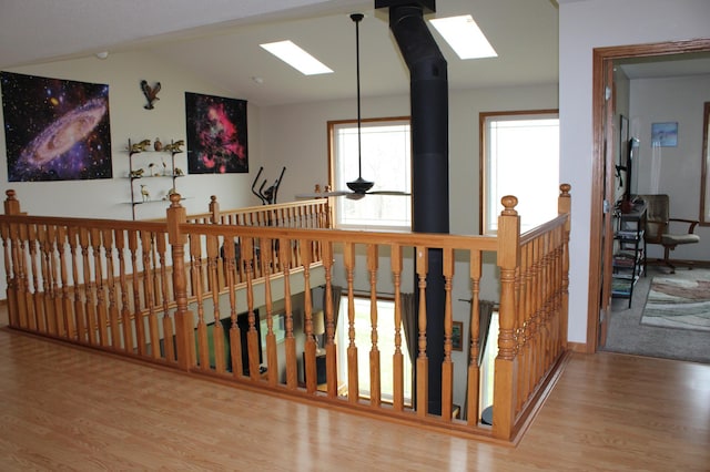 hallway featuring an upstairs landing, wood finished floors, and vaulted ceiling with skylight