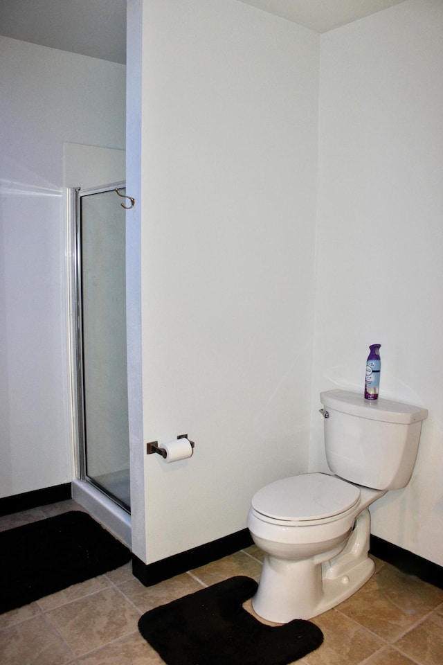 bathroom featuring baseboards, tile patterned floors, a stall shower, and toilet