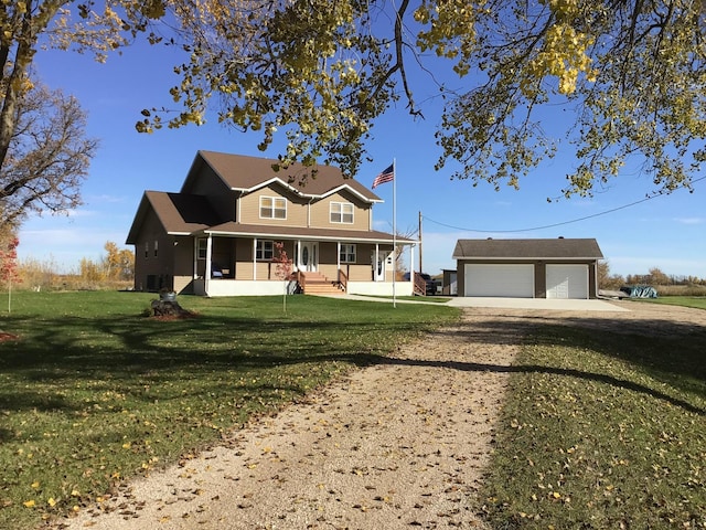 country-style home with a front yard, an outbuilding, a porch, driveway, and a detached garage