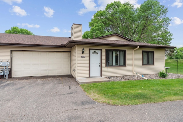 single story home with asphalt driveway, a chimney, a front lawn, a garage, and a shingled roof
