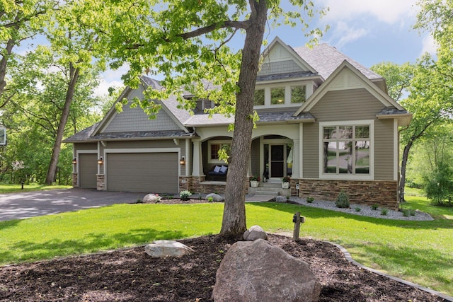 craftsman inspired home with driveway, covered porch, a front lawn, and a garage