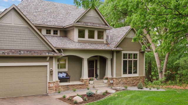 craftsman house featuring covered porch, stone siding, driveway, and a front yard