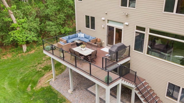 deck with an outdoor living space, a yard, and stairs