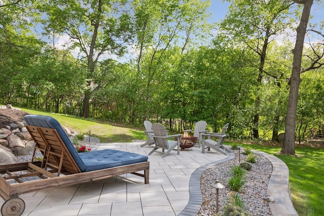 view of patio / terrace featuring an outdoor fire pit and view of scattered trees