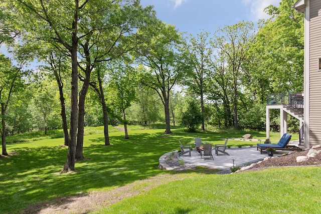 view of green lawn with a patio area, stairway, view of scattered trees, and a wooden deck