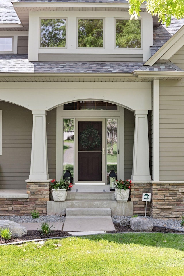 doorway to property featuring a porch, stone siding, and a high end roof