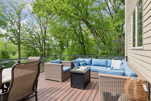 wooden terrace featuring an outdoor living space with a fire pit and view of wooded area