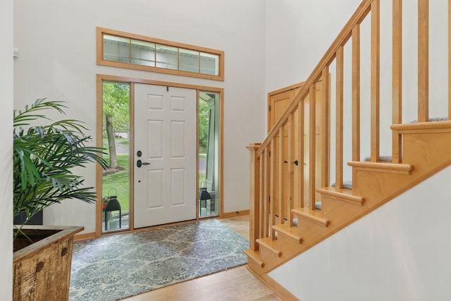 foyer entrance featuring stairs, wood finished floors, a high ceiling, and baseboards