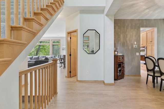 hall with light wood-type flooring and baseboards