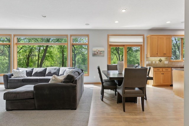 living area with healthy amount of natural light, recessed lighting, light wood-style flooring, and baseboards