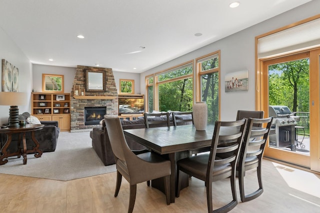dining area with light wood finished floors, recessed lighting, and a fireplace