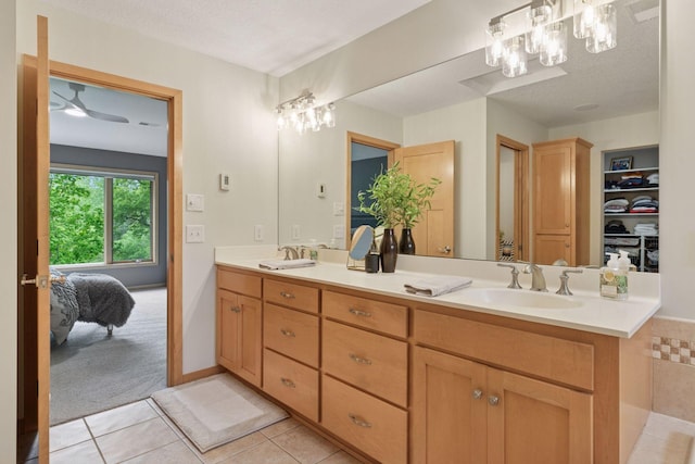 ensuite bathroom featuring tile patterned flooring, double vanity, a chandelier, and a textured ceiling