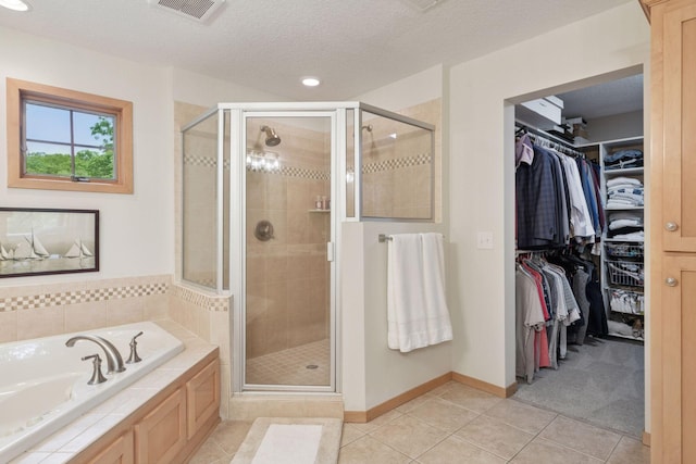 bathroom featuring tile patterned flooring, a stall shower, a spacious closet, a garden tub, and baseboards