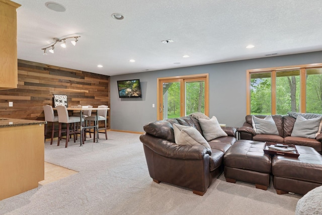 living room with light colored carpet, healthy amount of natural light, wooden walls, recessed lighting, and a textured ceiling